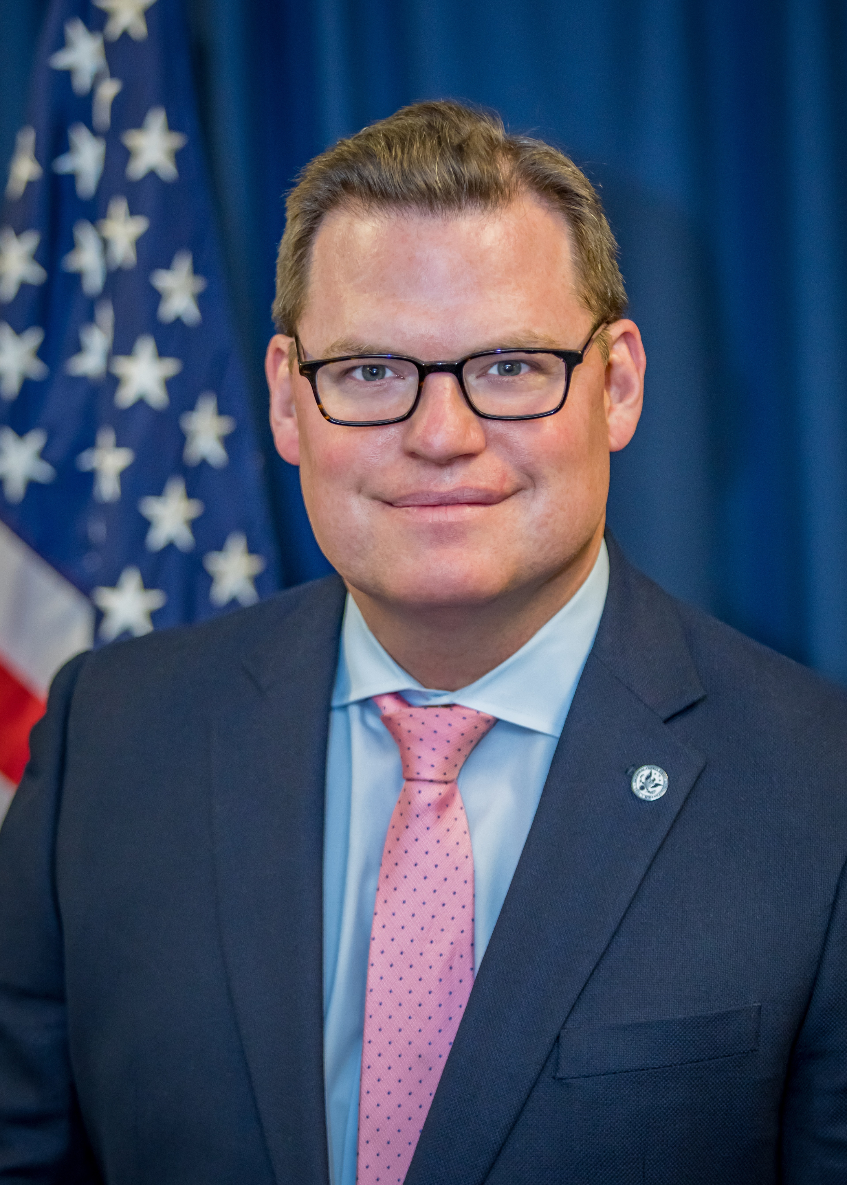 Portrait of a man with glasses wearing a gray shirt.