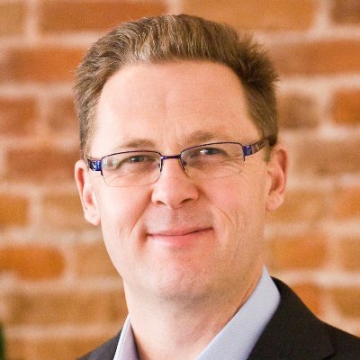 Portrait of a man with glasses wearing a gray shirt.