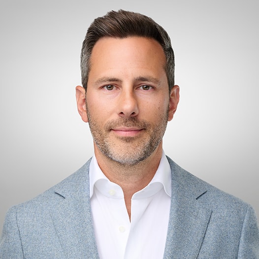 Portrait of a man with glasses wearing a gray shirt.