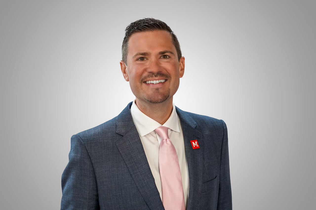 Portrait of a man with glasses wearing a gray shirt.